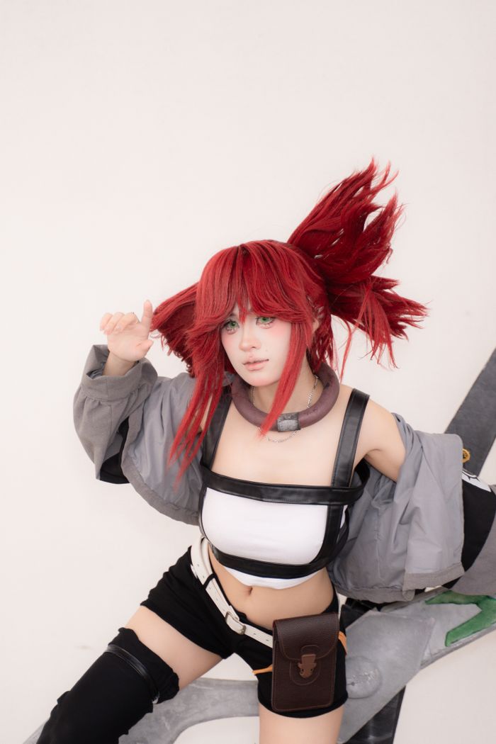 Energetic portrait of a woman in cosplay with red hair against a white background.